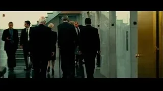 Six men in suits walking down hallway — Limitless