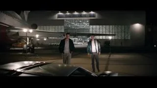 Man crouching on car hood in Shelby American hangar — Ford v Ferrari