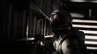 Man in space suit holding gun in dim room — Interstellar
