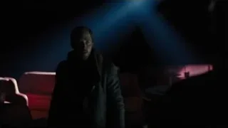 Man standing in dimly lit room with red and blue lights — Blade Runner 2049