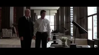 two men in modern office lobby with city view — Batman: The Dark Knight