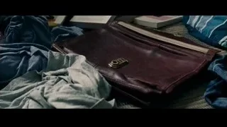Hand holding brown leather wallet on bed — The Amazing Spider Man 2