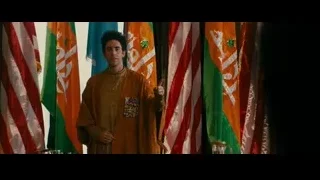 Man in brown robe standing before flags — The Dictator