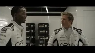 two men in racing suits in garage — F1