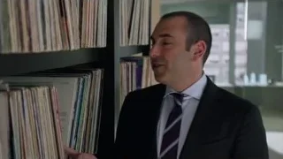 man in suit looking at vinyl records — Suits