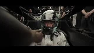 Man adjusting helmet in race car in garage — F1