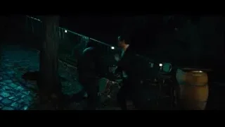 man in suit holding gun on cobblestone path — John Wick: Chapter 4