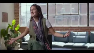 young woman smiling on living room couch — The Social Dilemma