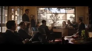Men in suits conversing in room with windows — Ford v Ferrari