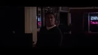 man in dimly lit room with neon sign — Creed