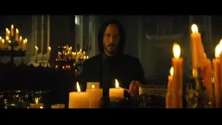 man sitting at table with many lit candles — John Wick: Chapter 4