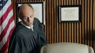 Judge in robe holding red object — Suits