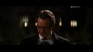 Man in suit speaking into microphone — Batman: The Dark Knight Rises
