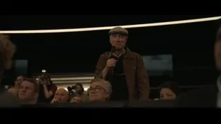 Elderly man speaking to crowd in auditorium — F1