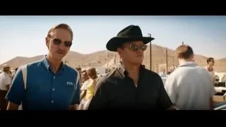 men in desert with mountains, one signing document — Ford v Ferrari