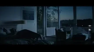 person sitting on bed in dimly lit bedroom — John Wick