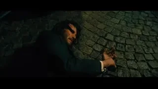 man with gun lying on cobblestone street — John Wick: Chapter 4