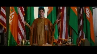 Man in golden robe speaking behind desk — The Dictator