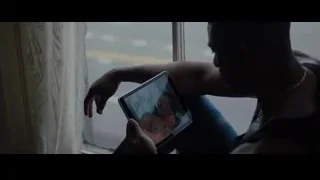 man sitting on window sill looking at cityscape — Creed 2