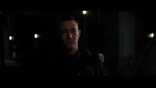 Man speaking into microphone in dimly lit room — Batman: The Dark Knight Rises