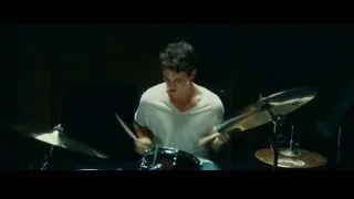 Young man playing drums in dimly lit room — Whiplash