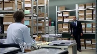 men talking in warehouse with boxes — Suits