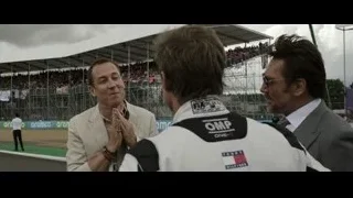 Three men conversing on race track with crowd — F1