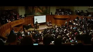 people in auditorium listening to speaker — Lucy