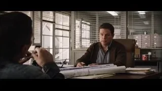 Two men conversing at office desk with blueprints — Ford v Ferrari