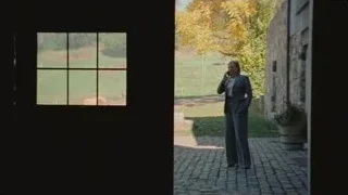 Woman in suit talking on phone in barn doorway — Succession