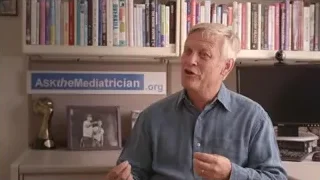 Older man explaining by 'AsktheMediatrician' sign — Screened Out