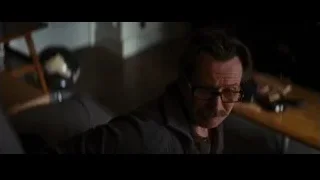 man with mustache and glasses sitting in dark room — Batman: The Dark Knight Rises