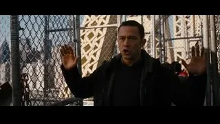 man behind fence with hands up cityscape — Batman: The Dark Knight Rises