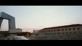van driving past arch-shaped city building — The Karate Kid