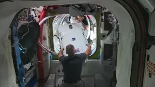 Two men working on space capsule inside station — Elon Musk: Return to Space