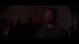 Man standing in dimly lit room with people — Creed 3