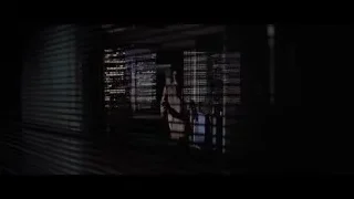 man looking out window at night city — American Psycho
