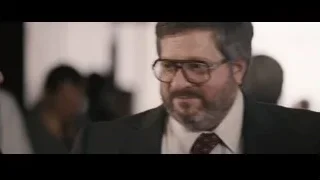 Man in suit looking at tie with flower — The Big Short