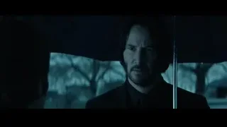 Keanu Reeves in suit holding umbrella in rain — John Wick