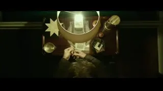 Person at wooden table with lamp — John Wick