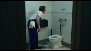 Man in blue apron cleaning toilet — The Bear
