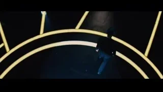 man in suit on stage with yellow lights — Now You See Me