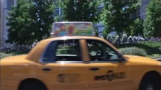 Taxi driving past city fountain — Suits