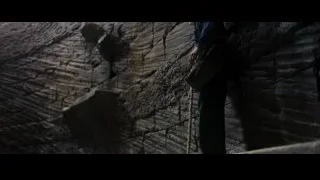 Person standing in dark cave holding rope — Batman: The Dark Knight Rises