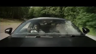 Two men driving black sports car — F1