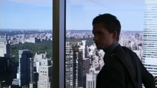 Man looking out large window at cityscape — Suits