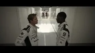 Two men in racing suits in hallway — F1