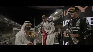 Three men celebrating with trophies on podium — F1