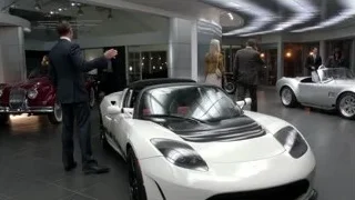 People admiring white sports car in showroom — Suits