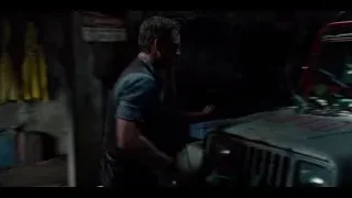 Man leaning over rusted car in forest — Jurassic World